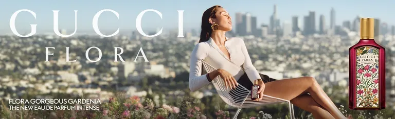 Gucci Flora Gorgeous Gardenia Intense: vrouw in een stoel boven een stad naast een rode parfumfles met bloemen